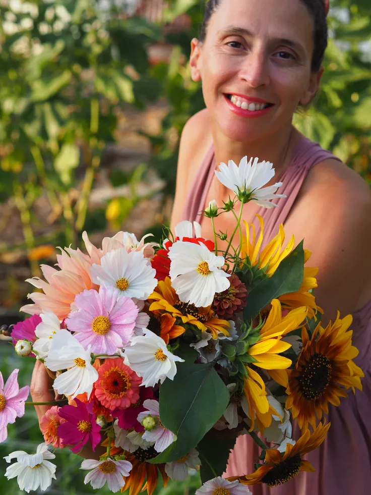 Priscila segurando um buquê de flores cultivadas localmente
